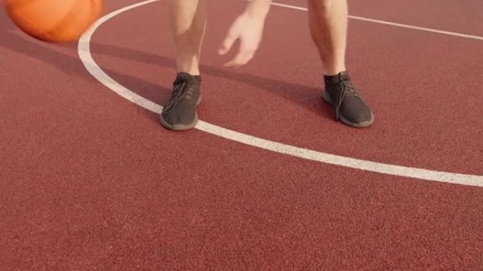 夏天，一个男人的腿通过在室外球场上两腿之间滚动篮球来练习球技