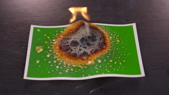 用燃气燃烧器在黑色背景上燃烧绿色照片。旧蓝牌烧坏了。图片的背景会从气体和火的高温中融化塑料