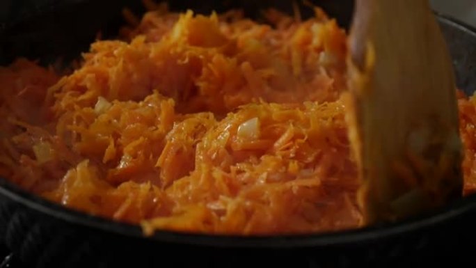 用油在平底锅中煎炸洋葱和磨碎的胡萝卜。用木铲在煎锅中搅拌