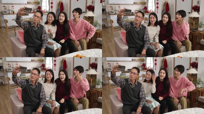 在农历新年假期期间，亚洲家庭在家里通过智能手机上的视频聊天与朋友进行现场交谈时，挥舞着手并试图获得消