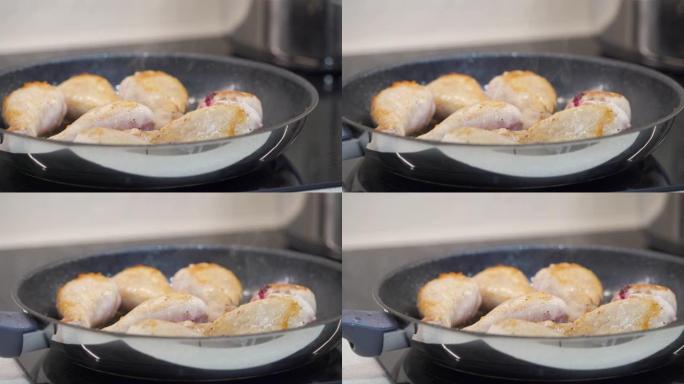 在厨房的电炉上的煎锅里炸鸡鸡腿。