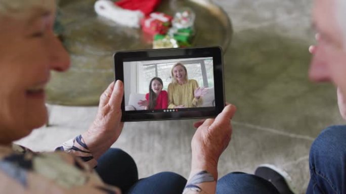 白人高级夫妇微笑着使用平板电脑与家人在屏幕上进行圣诞节视频通话