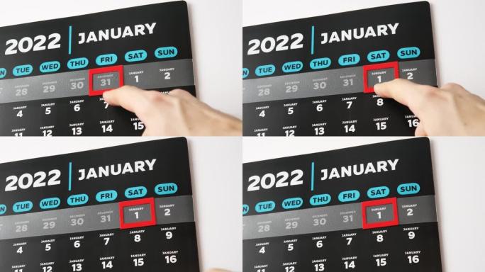 挂历2022的黑色美丽1月页面的特写镜头，男性手将红色光标移至第一个日期
