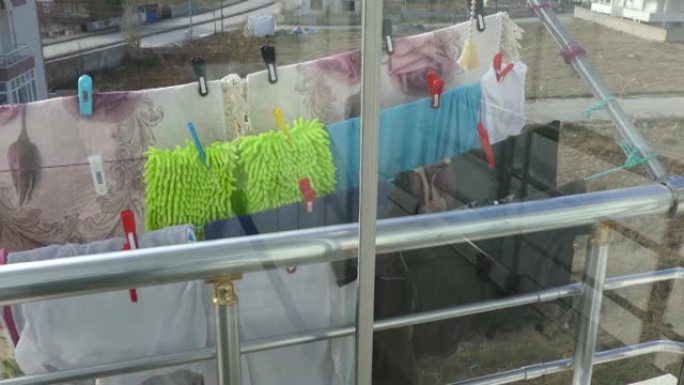 在阳台上晾干衣服的特写镜头，晾衣绳上挂着衣服，阳台上有晾衣夹，