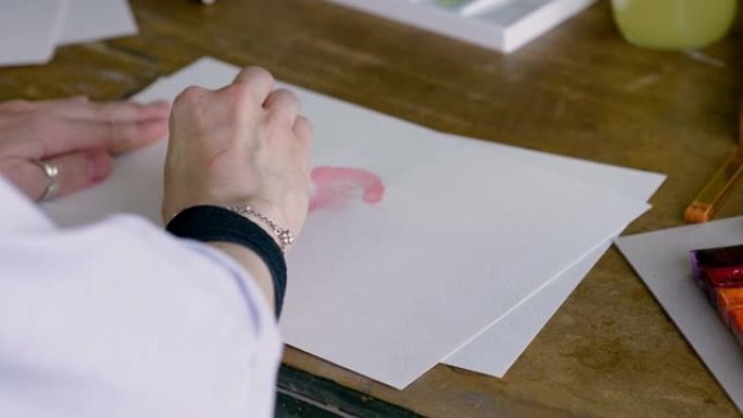 女艺术家的手用画笔用水彩画了一颗红色的心。4K