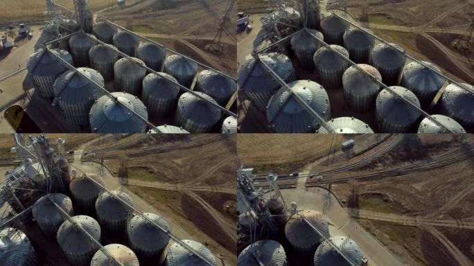 晴天，空中无人机在电梯的圆形金属桶上飞行。储粮用圆形钢筋混凝土结构俯视图。谷物电梯建筑群。干燥和储存