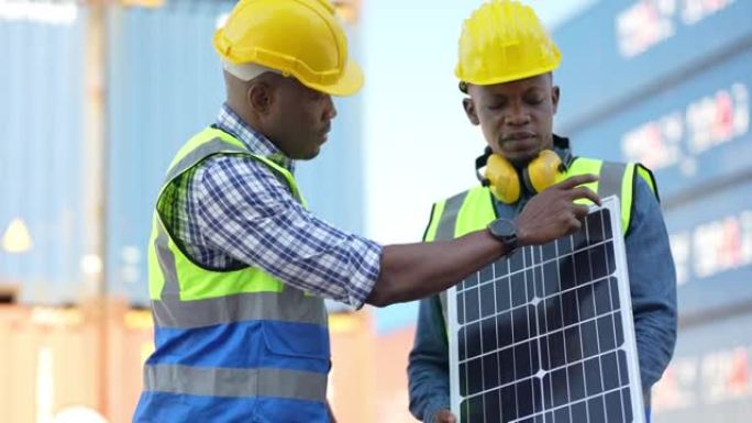 非洲工厂在室外测试太阳能电池。商业工程师会见创新高效的可再生能源太阳能电池板。在集装箱背景前操作的智