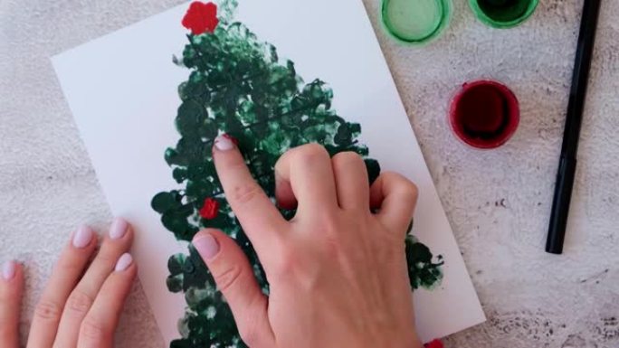 用手指画画快乐圣诞树。DIY制作贺卡儿童节日手工工艺品。一步一步。新年快乐圣诞树装饰