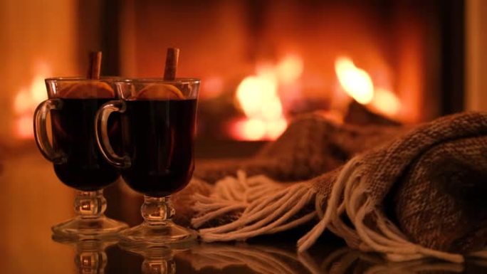 壁炉背景上有两杯热葡萄酒和格子。
