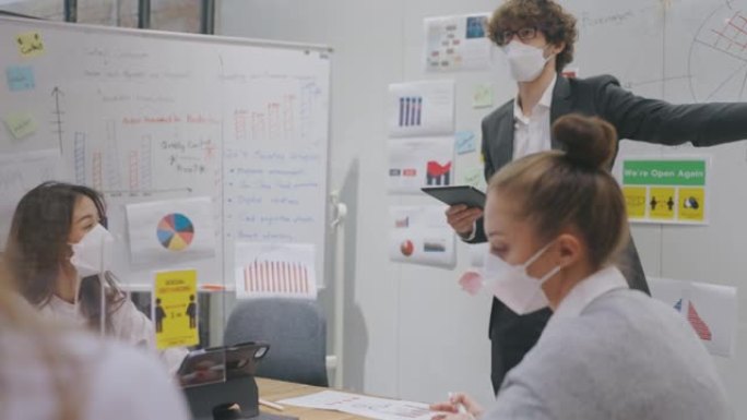在新型冠状病毒肺炎大流行期间，一群戴着防护口罩的商人坐在办公桌前，打喷嚏，并在银行办公室使用计算机