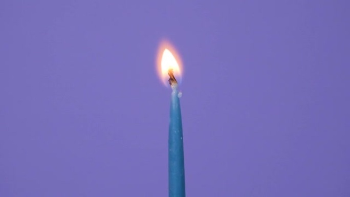 在闪电上关闭生日蛋糕上的蜡烛。关闭紫色背景上燃烧的蓝色蛋糕蜡烛。全高清分辨率慢动作生日快乐或周年纪念