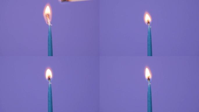 在闪电上关闭生日蛋糕上的蜡烛。关闭紫色背景上燃烧的蓝色蛋糕蜡烛。全高清分辨率慢动作生日快乐或周年纪念