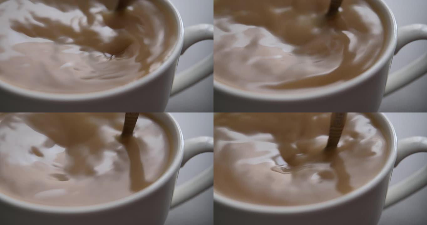 新鲜的早晨在红茶和牛奶特写。选择性聚焦。慢动作俯视图人手搅拌杯热巧克力或咖啡。慢动作男人在一杯芳香咖