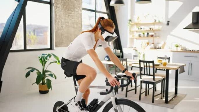 戴VR眼镜的年轻女子正在踩踏室内自行车教练。工作室公寓，厨房。在家进行日常训练。慢动作