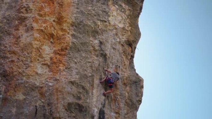 强壮和熟练的男子攀登者攀爬石灰石垂直峭壁挑战性的路线，艰苦的努力，抓住。极限运动和健康的生活方式