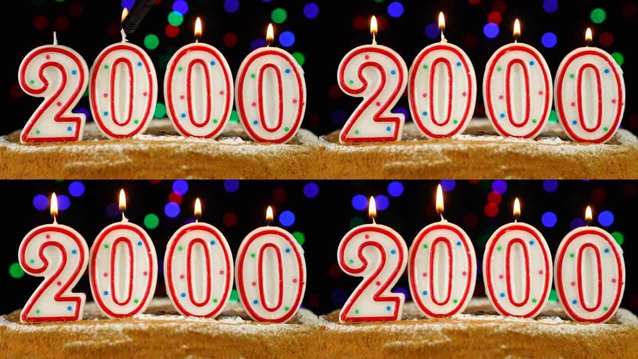 生日蛋糕与白色燃烧的蜡烛在数字2000的形式