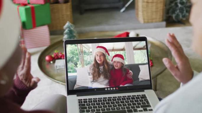 多元化的高级女性朋友使用笔记本电脑与屏幕上的幸福家庭进行圣诞节视频通话