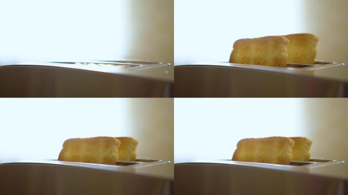 从电烤面包机中弹出的烤白面包切片。厨房烤面包机慢动作在早餐特写时制作烤面包。烤吐司面包从烤面包机上弹