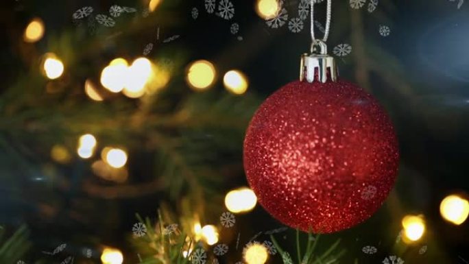 雪花漂浮在圣诞树上悬挂的红色摆设的特写视图上