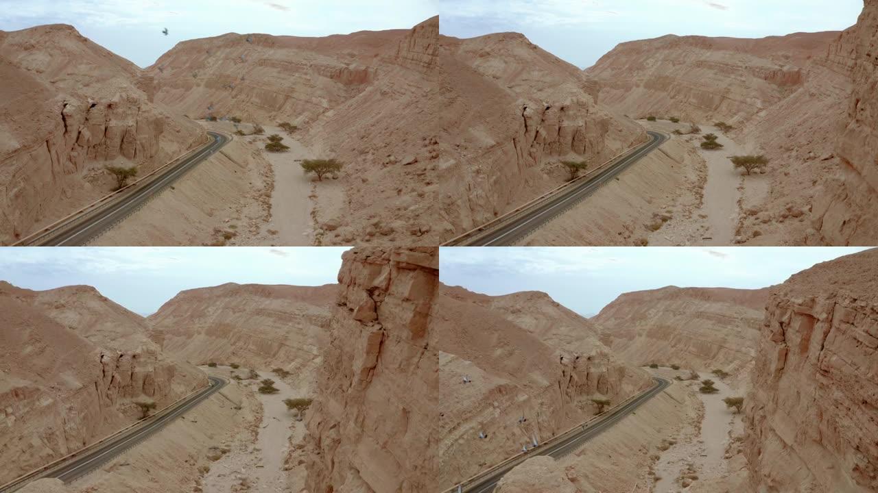 无人机在镜头前观察沙漠山脉的道路和岩层之字形飞鸟