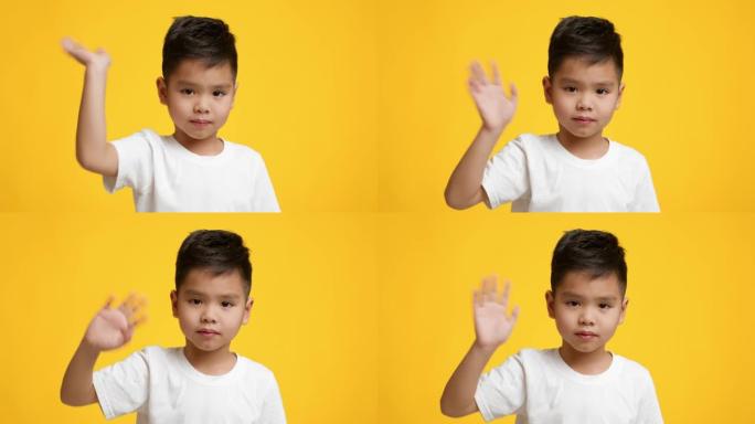 亚洲小男孩挥舞着手看着相机，黄色背景