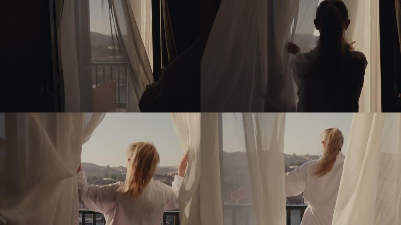 慢动作: 走向房间窗户的年轻女子打开窗帘，走到阳台上。埃及阿斯旺早上壮观的河景和帆船