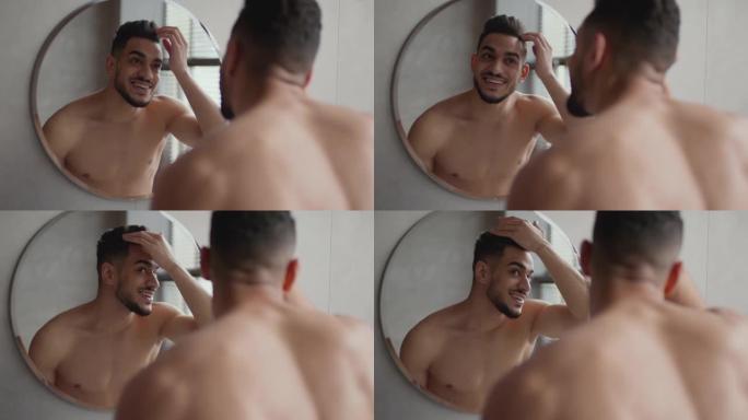 年轻积极时尚的阿拉伯男人在浴室照镜子，在出门前整理发型