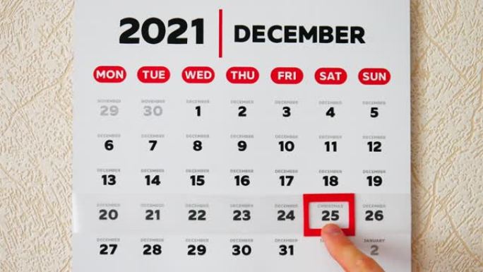 挂历2021的美丽12月页和一个男性手指将红色光标移动到圣诞节约会特写
