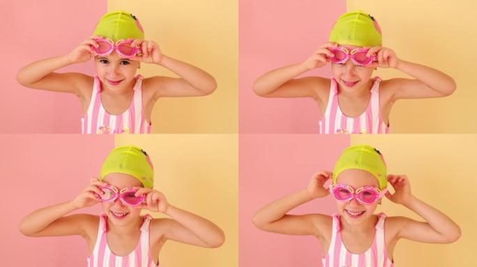 一个戴着游泳帽和条纹粉红色泳衣的女孩戴着螃蟹形状的有趣的儿童泳镜。