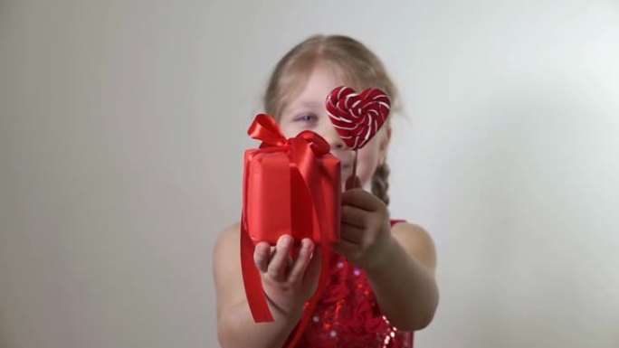 女孩在红色礼品盒和心形棒棒糖中赠送礼物。概念是儿童的祝贺，节日，给予。2月14日度假，圣诞节，母亲节