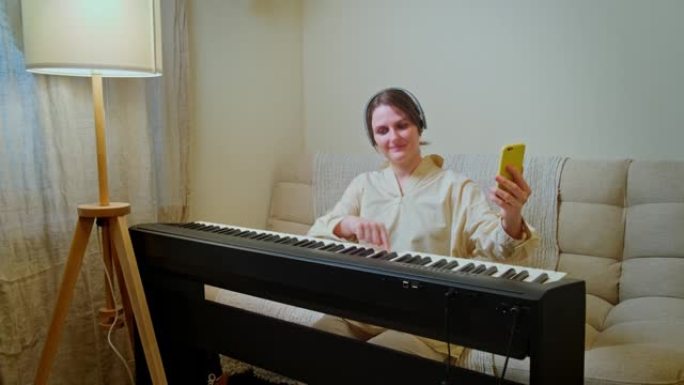快乐女人音乐家与钢琴在客厅沙发上看手机