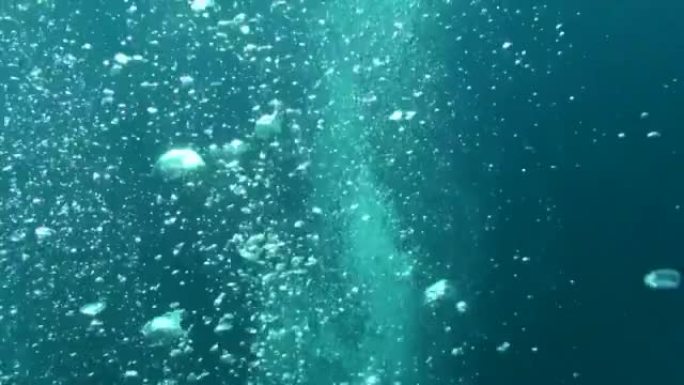 水肺潜水员的气泡上升到阳光明媚的海面