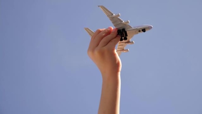 一个小孩在蓝天背景下拿着模型飞机的特写镜头