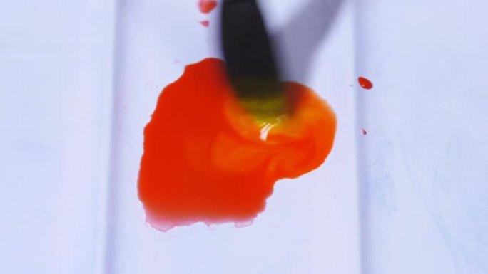 艺术家用画笔将水彩颜料混合在调色板中。