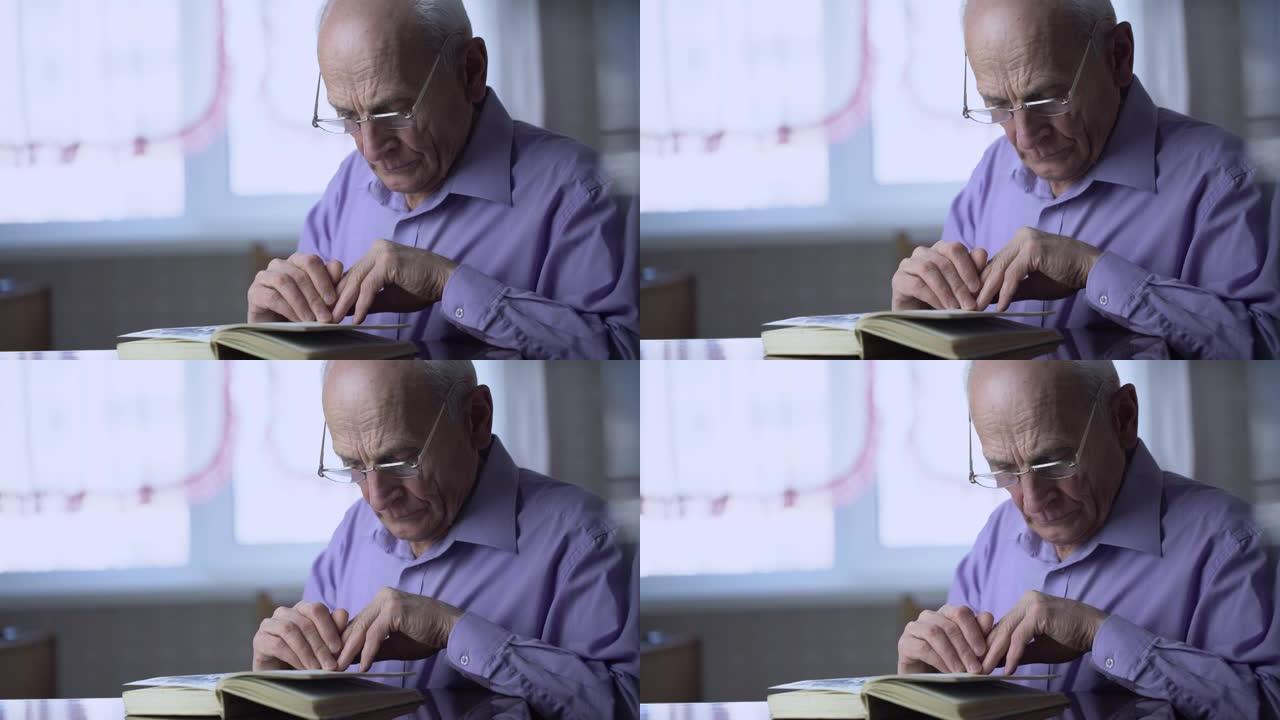 一位戴眼镜的70岁老人坐在木桌旁看书