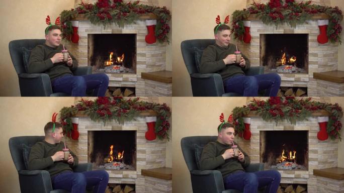 一个年轻人坐在壁炉旁的扶手椅上，头上长着角，喝可可。圣诞气氛。