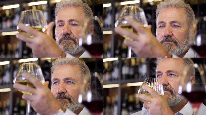 一位老人，胡须，白发，穿着考究的侍酒师，男性酿酒师，品尝香气并检查倒入透明玻璃杯中的红酒的质量。酿酒