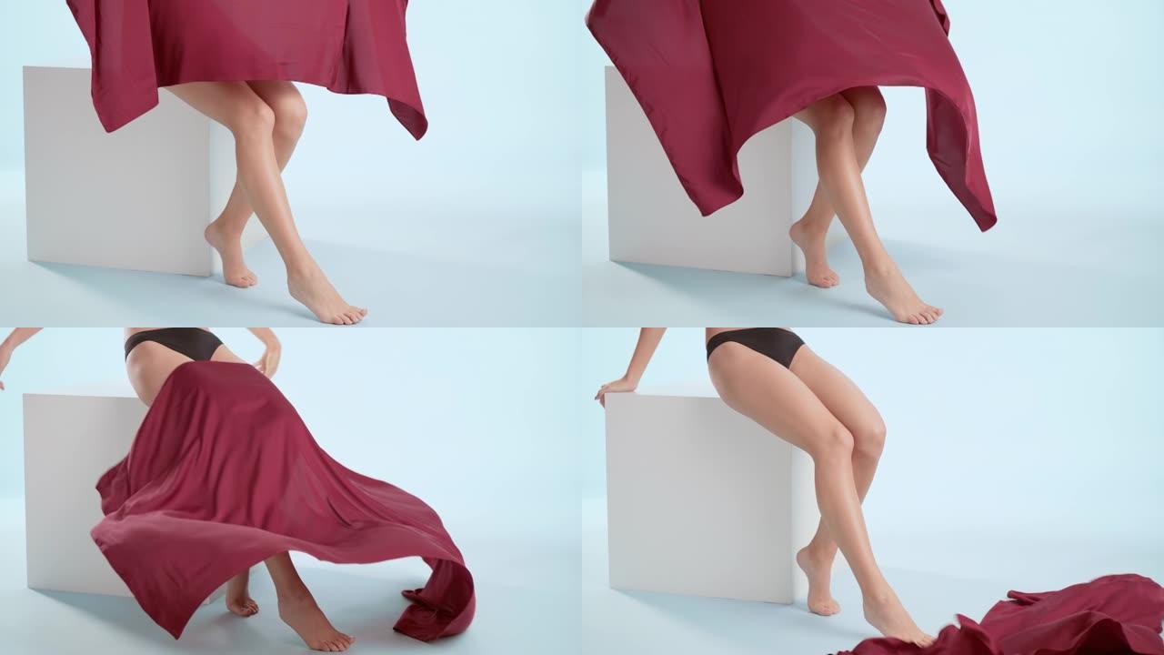女人在坐在立方体上的腿上扔一块红布