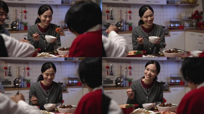 在春节前夕，有选择性的焦点微笑的亚洲daughter妇在餐桌上的碗里从她的老母亲那里接受食物