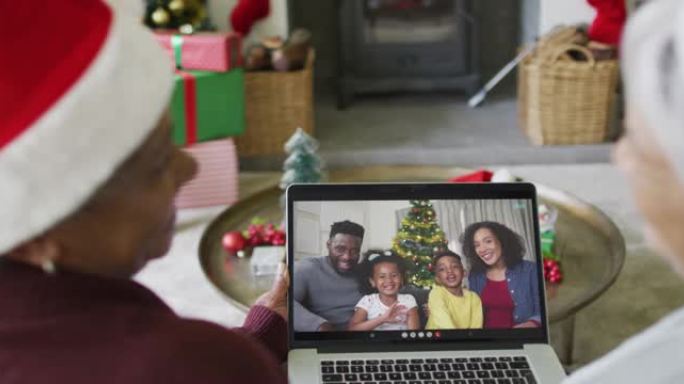 多元化的高级女性朋友使用笔记本电脑进行圣诞节视频通话，屏幕上有微笑的家人