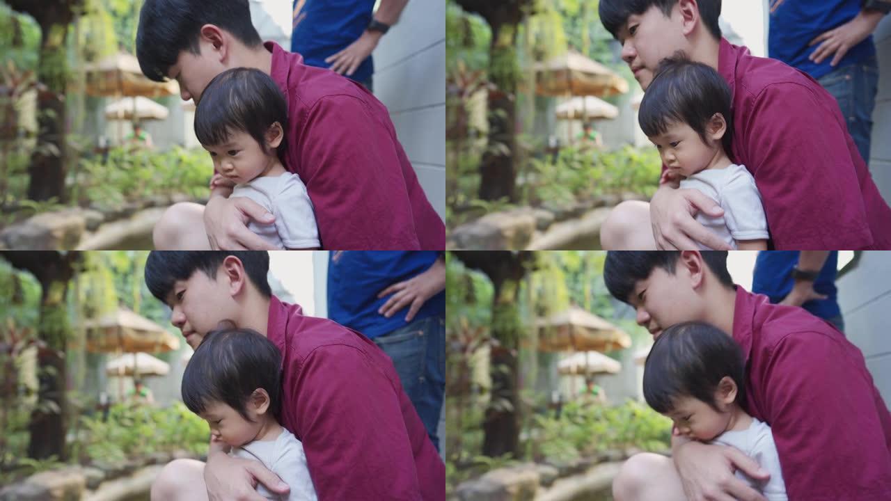 亚洲年轻的爸爸抱着他可爱的女婴女儿，同时在外面的好天气中度过时光，父女纽带，爱照顾家人，真正的亚洲家