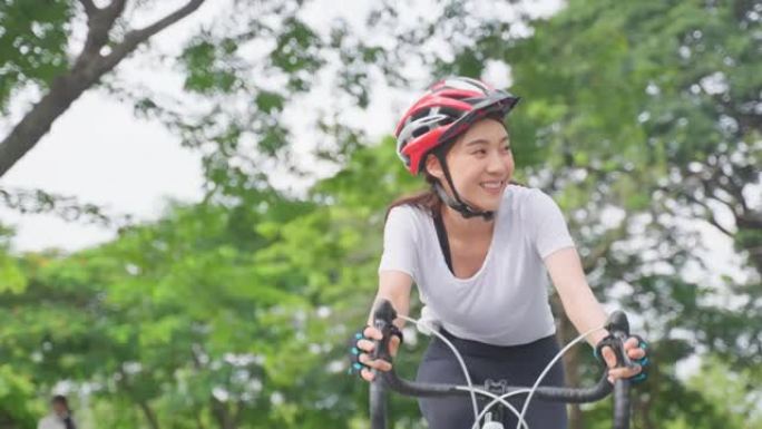 亚洲年轻美女骑自行车在公园健康。穿着运动服的活跃运动员运动女孩感到新鲜和放松，晚上通过骑自行车锻炼来