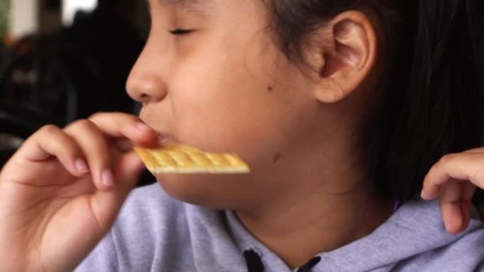 一个黑发小女孩在等待食物时在餐厅吃苏打饼干的特写镜头