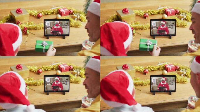 带有圣诞老人帽子的高加索父子使用平板电脑进行圣诞视频通话屏幕上的圣诞老人