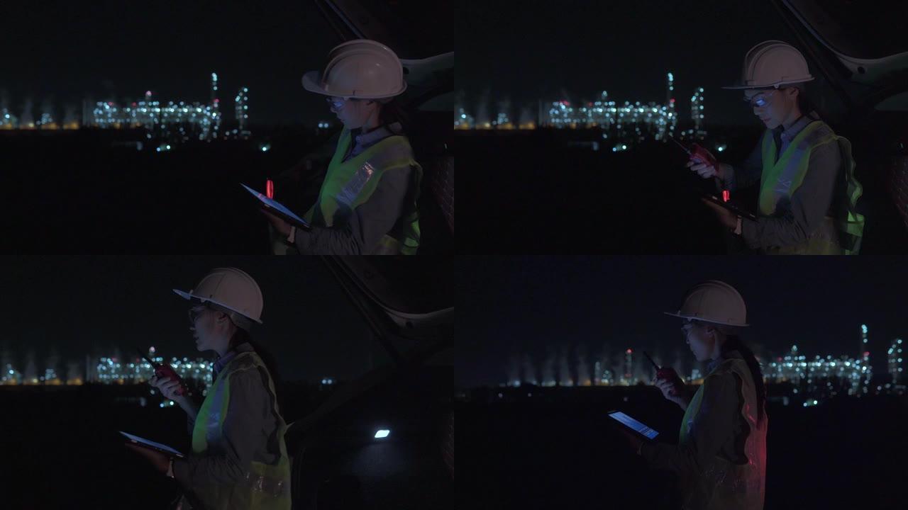 穿着制服的女主管使用数字平板电脑在工业区的石油炼油厂工作深夜