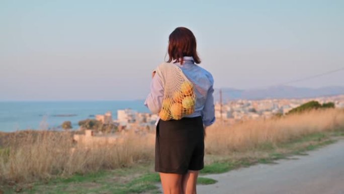 中年妇女，带着一袋新鲜橘子享受大自然、日落、海景
