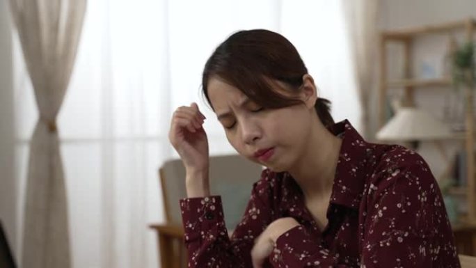 紧张的亚洲日本妇女使用笔记本电脑。健忘的女商人在电脑上过度劳累后头痛。在家工作时，疲倦的沮丧女士按摩