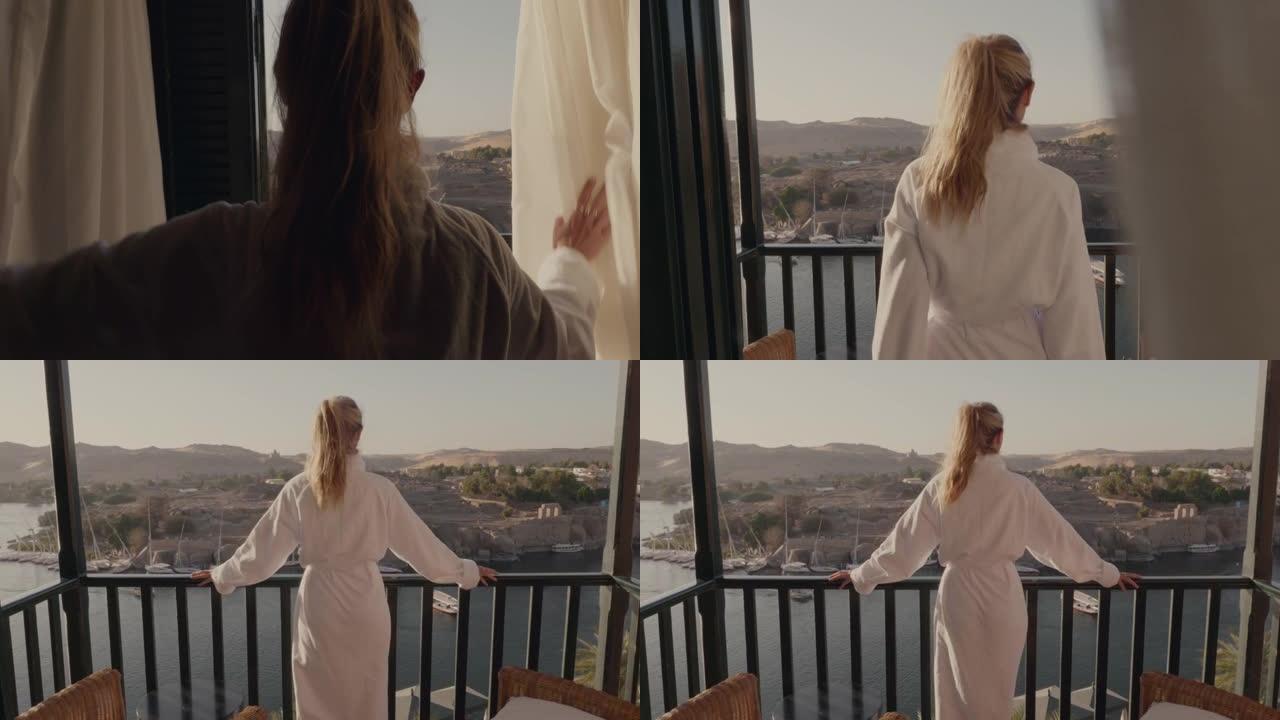 特写后景年轻女子打开窗帘站在阳台上的豪华酒店房间里，早上欣赏迷人的河景