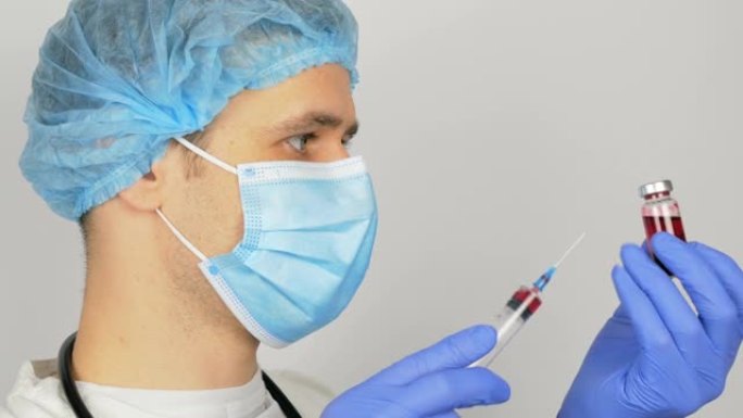 年轻英俊的医生为新型冠状病毒肺炎疫苗接种做准备，在注射前用疫苗准备注射器。医生用红色疫苗填充注射器，