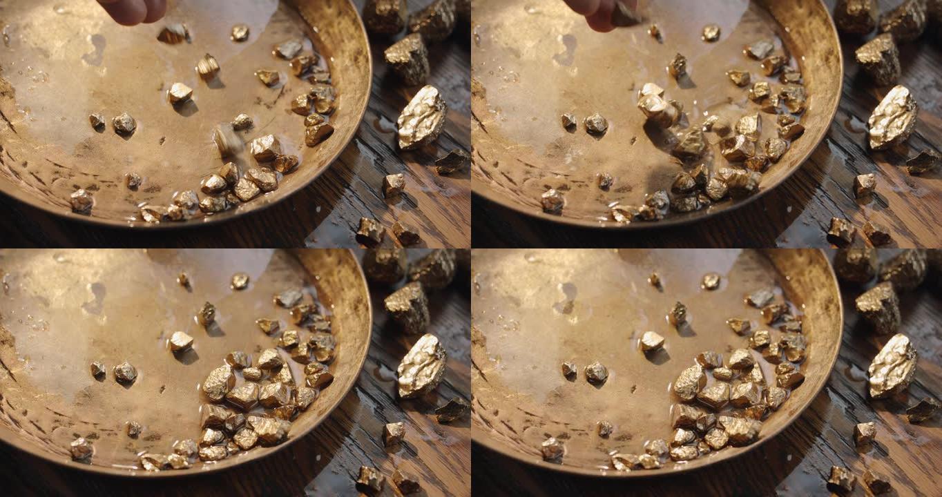 金块慢慢掉进了一个铜制的老式淘金碗里。慢动作150 fps 4k视频。